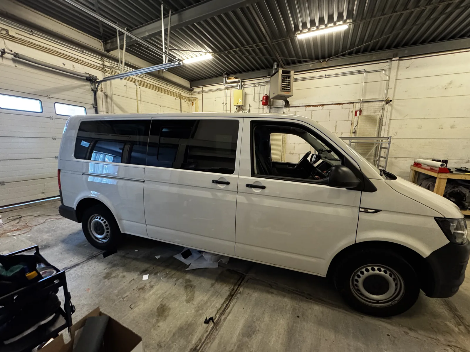 Witte bedrijfsbus met donker afgewerkte zijruiten in de werkplaats